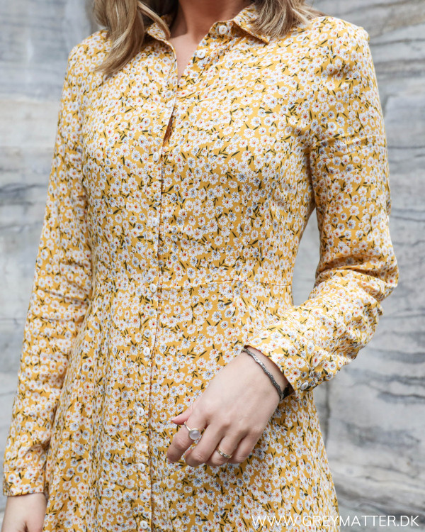 Lang kjole med blomsterprint i gule farver set tæt på